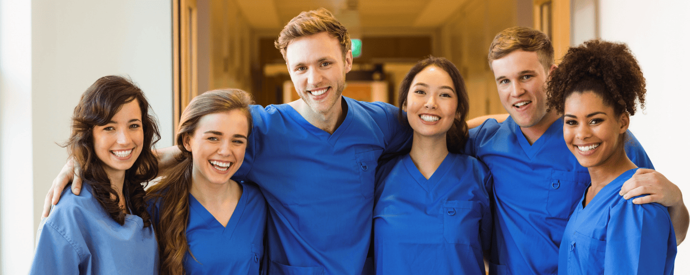 PA students in blue scrubs smiling together